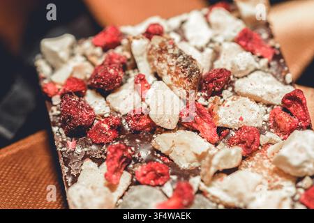 Nahaufnahme der Textur einer handgefertigten Artisan-Schokoladenriegel mit gefrorenen Erdbeeren und weißen Schokoladenstücken, ein Gourmet-Dessertgenuss Stockfoto