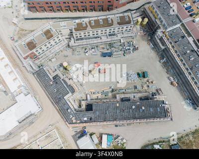 Luftaufnahme einer Baustelle mit modernen Gebäuden mit Flachdächern, Baumaterialien und Erdarbeiten in den Niederlanden. Stockfoto