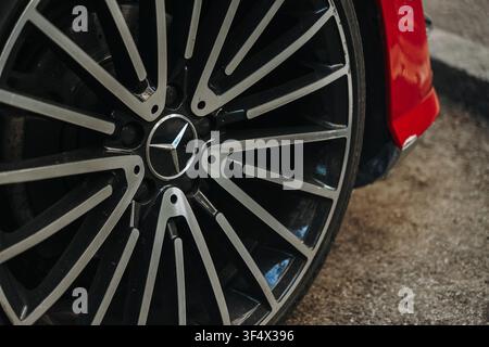 Belgrad, Serbien - 23. Juli 2026. Nahaufnahme eines Mercedes-Benz AMG-Alufelgens, das an einem roten Pkw montiert ist. Stockfoto