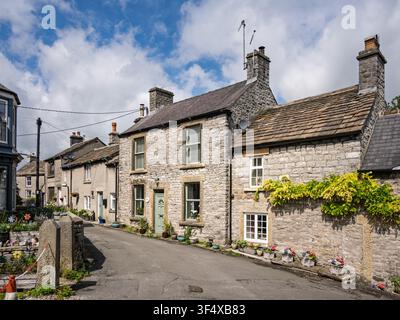 Traditionelle Kalksteinhäuser zeigen feine Steingewände und Sockelverzierungen entlang einer schmalen historischen Dorfstraße in Bradwell, Peak District, England Stockfoto