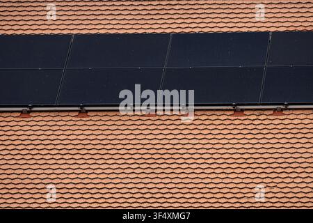 Solarphotovoltaikpanele, die auf einem Ziegeldach einer Wohngebäude installiert sind, produzieren erneuerbare Energie in der Schweiz. Stockfoto