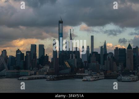 Blick auf die Skyline von Manhattan mit markanten Wolkenkratzern unter einem dramatischen bewölkten Himmel bei Sonnenuntergang in New York, New York, Vereinigte Staaten. Stockfoto