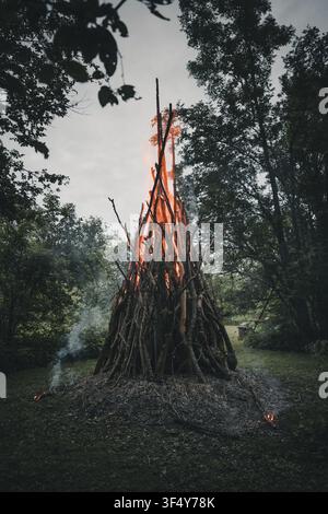 Ansicht eines traditionellen Mittsommerfeuers, das hell mit hohen Flammen und glühenden Kohlen auf einer Waldlichtung in Vormsi, Laane County, Estland brennt. Stockfoto