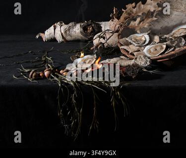 Leben vom Land: Stillleben mit Zutaten für Austern, die in einer Algenbrühe gedünstet und mit Eichelnmehl angedickt sind, und über einem Lagerfeuer gekocht wurden. Stockfoto