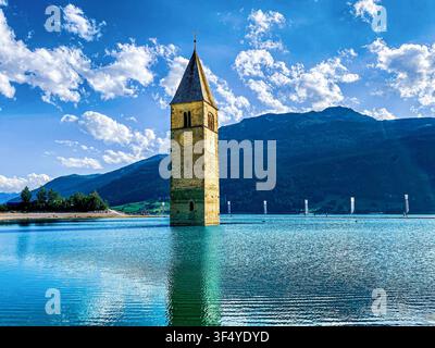 Historischer untergegangener Glockenturm der Kirche St. Katharina, der aus dem türkisfarbenen Wasser des Reschensees in Südtirol, Italien, aufsteigt Stockfoto