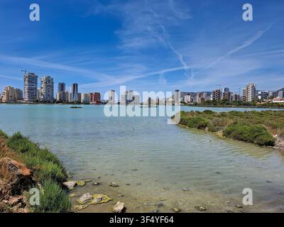 Eine Weitwinkelansicht über einen Salzsee mit einer modernen Stadtsilhouette im Hintergrund. Der Himmel ist klar und blau und schafft eine helle Atmosphäre. Stockfoto