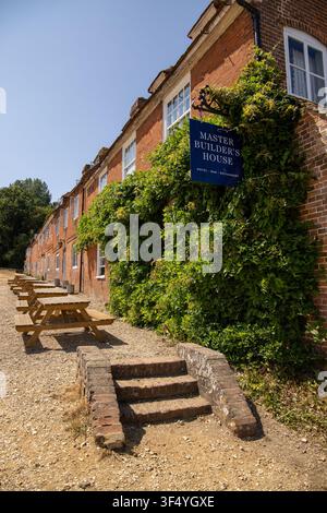 Das historische rote Backstein-Gasthaus Master Builders House in Bucklers Hard Hampshire mit üppigem grünem Efeu und Picknicktischen draußen an einem sonnigen Tag Stockfoto