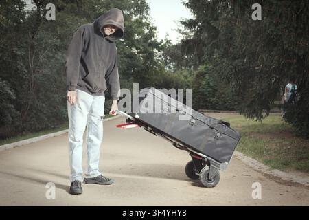 Mann in schwarzem Hoodie organisiert und bereitet professionelle Kameraausrüstung im Freien vor Stockfoto
