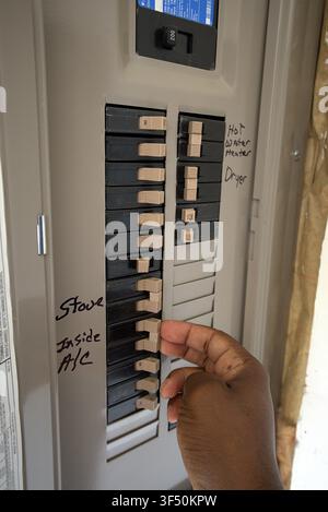 Hand, die den Leistungsschalter in der Hausstromschaltung zurücksetzt - Konzept der Stromwartung. Stockfoto