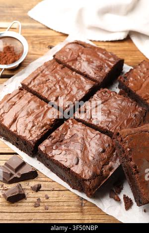Leckere Brownies und Schokoladenstückchen auf Holztablett, Nahaufnahme Stockfoto