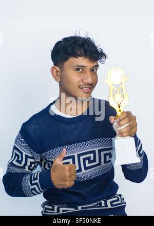 Glücklicher junger Mann hält goldene Trophäe und lacht isoliert auf Weiß Stockfoto