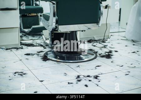 Fußboden eines Friseursalons mit geschnittenem Haar und professionellem Vintage-Stuhl Stockfoto