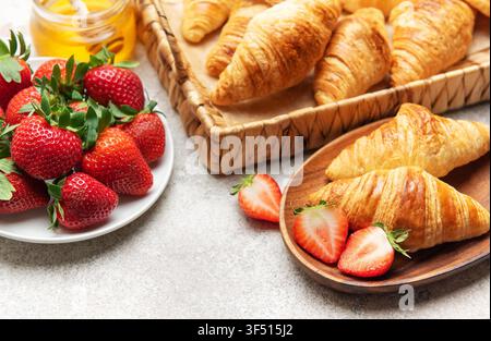 Frisch gebackene Croissants werden mit Erdbeeren und Honig serviert und sorgen so für ein köstliches Frühstück Stockfoto
