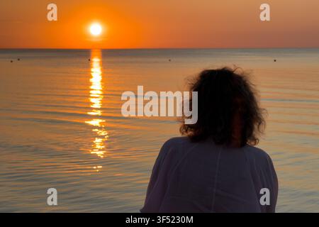 Lettland. 30. Juli 2026. Eine Frau schaut zu, während die Sonne über der Ostsee in Jurmala, Litauen, am 30. Juli 2026 untergeht. (Foto von Jaap Arriens/Sipa USA) Credit: Sipa USA/Alamy Live News Stockfoto