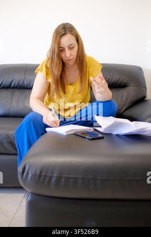 Frau, die Rechnungen berechnet und die persönlichen Finanzen zu Hause verwaltet, gestresst wegen eines Budgets Stockfoto