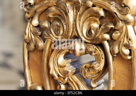 Nahaufnahme einer kunstvoll vergoldeten Holzschnitzerei mit barocken Rankenwerk, Blattgoldpatina und geschnitzten Blumenmotiven, die Textur und Handwerkskunst hervorhebt Stockfoto