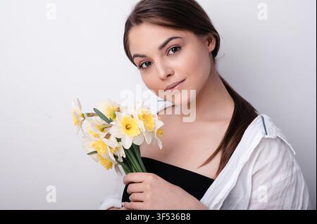 Brünette Frau hält Narzissenblumen Stockfoto