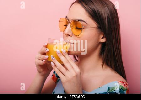 Brünette Frau trinkt Orangensaft Stockfoto
