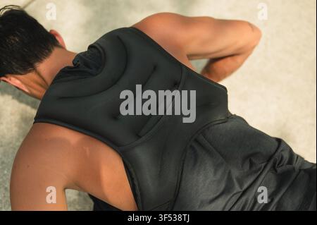 Mann macht Liegestütze, während er eine Gewichtsveste trägt Stockfoto