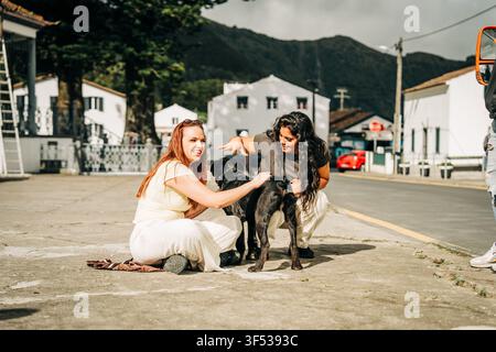 Zwei Freundinnen lachen, während sie einen Hund streicheln Stockfoto