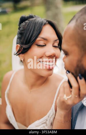 Schöne Braut berührt liebevoll das Gesicht ihres Bräutigams Stockfoto