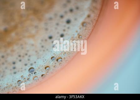Extrem naher Makroaufnahmeblick auf reiche Kaffeekrema und zarte Blasen, die sich in einer Keramiktasse bilden, wobei die glatte Textur und das warme braune Getränk betont werden Stockfoto