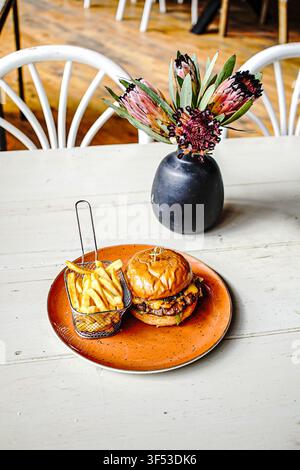 Gourmet-Cheeseburger und Pommes auf einem rustikalen Tisch Stockfoto