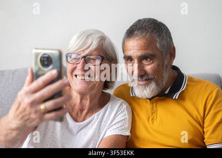 Zufriedenes Seniorenehepaar macht Selfie mit Smartphone zu Hause Stockfoto