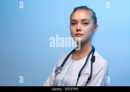 Ärztin mit Stethoskop, die vor blauem Hintergrund posiert Stockfoto