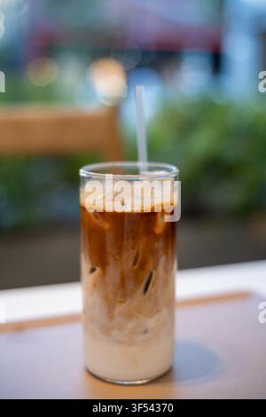 Ein Glas Eiskaffee mit sichtbaren Schichten von Milch und Kaffee auf einem Tablett, aus einem Hochwinkel gesehen. Stockfoto