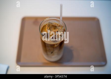 Ein Glas Eiskaffee mit sichtbaren Schichten von Milch und Kaffee auf einem Tablett, aus einem Hochwinkel gesehen. Stockfoto