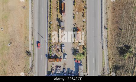 Luftaufnahme einer zweispurigen Autobahn mit zentralem Wartungshof und geparkten Lastwagen in Griechenland für Straßenverkehrs-Bildmaterial Stockfoto
