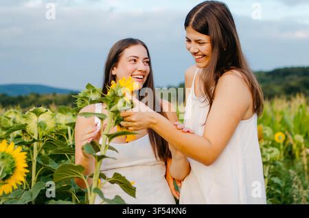 Zwei schöne junge Frauen haben Spaß in einer Sonnenblume Stockfoto