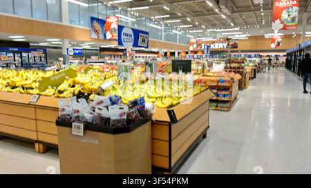 Toronto, ON, Kanada – 30. Juli 2026: Kunden kaufen frische Bananen und verschiedene Früchte in der Obst- und Gemüseabteilung eines hell erleuchteten Supermarkts. Stockfoto