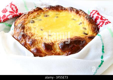 Traditionelles österliches Süßbrot gefüllt mit Hüttenkäse und Rosinen, in besticktes Handtuch gewickelt. Stockfoto für Back- und Feiertagskonzepte. Stockfoto