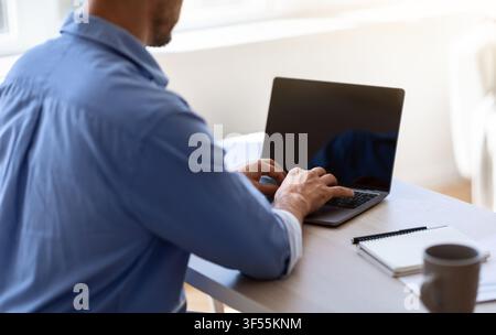Unkenntlich Geschäftsmann arbeiten auf Laptop mit schwarzem Bildschirm im Büro, mockup Bild Stockfoto