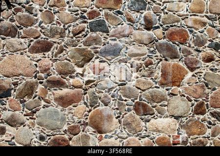 Alte Feldsteinmauer als Hintergrundtextur. Traditionelle europäische rustikale Steinmauer im Nahaufnahme. Stockfoto