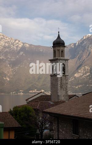 Kirchturm mit Blick über den Gardasee und schneebedeckten Bergen im Hintergrund, Limone sul Garda, Lombardei, Italien. Stockfoto