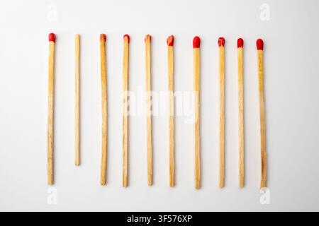 Holzsicherheitsstreiche mit roten Köpfen, die als untere Bordüre auf einem sauberen weißen Hintergrund angeordnet sind. Stockfoto