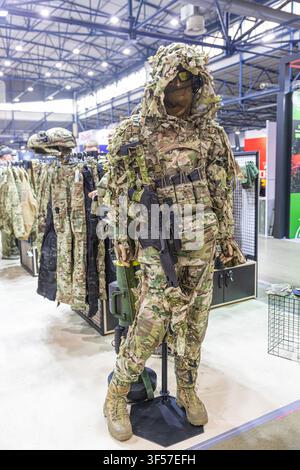 Getarntes Schaufensterpuppenmodell in taktischer Ausrüstung, mit kompletter Uniform inklusive Gewehr, Helm und Schutzbrille, auf einem Ständer in einer Ausstellungsfläche ausgestellt, hohe Decke Stockfoto