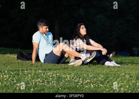 Ein junges Paar sitzt zusammen auf dem Rasen im Boston Common, Boston, Massachusetts. Stockfoto
