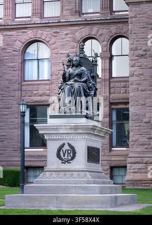 Toronto, Ontario, Kanada – 06 21 2025: Eine vertikale Aufnahme zeigt die Bronzeskulptur von Königin Victoria, die auf einem verzierten Thron auf einem Granitpiedestal sitzt Stockfoto