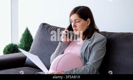 Schwangere Geschäftsfrau, die von zu Hause aus arbeitet und einen Anruf tätigt Stockfoto