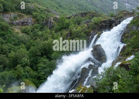 Donnernder Gletscherwasserfall stürzt über moosbedeckte Felsen nahe Briksdalsbreen, Norwegen, ideal für Natur- und Reisekonzepte. Stockfoto