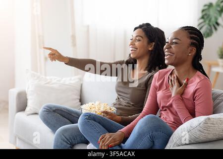 Zwei schwarze Freundinnen, die Spaß zu Hause haben, Comedy ansehen Stockfoto