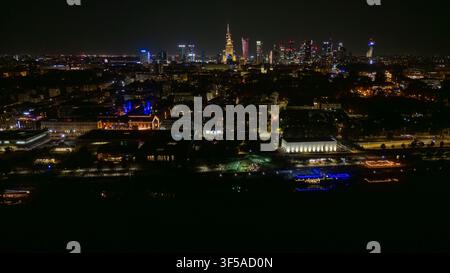 Nachtansicht über Warschau mit beleuchteten Hochhäusern, leuchtenden Straßen und dichten städtischen Dächern, wobei der zentrale Turm sich gegen den dunklen Himmel und verstreute Stadtlichter abhebt Stockfoto