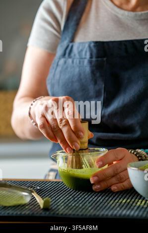 Hände mischen grünes Pulver mit Bambusrührer zur Vorbereitung eines Morgen-Matcha-Getränks Stockfoto