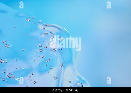 Makro einer durchscheinenden blauen Flüssigkeits- oder Geloberfläche mit verstreuten Luftblasen und weichen fließenden Formen auf einem blassen Farbverlaufshintergrund. Saubere abstrakte Textur Stockfoto
