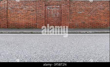 Moosige Mauer am Straßenrand. Grau gefliester Bürgersteig und Straße vor dem Hotel. Hintergrund für Kopierbereich. Stockfoto