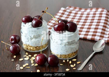 Zwei Gläser Overnight-Oats mit Kirschen auf einem Holztisch Stockfoto